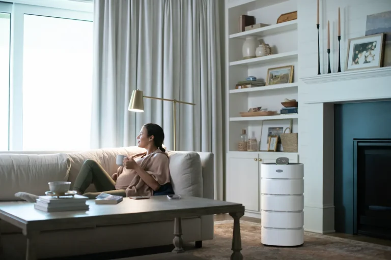 Woman sitting on couch with an air purifier next to it